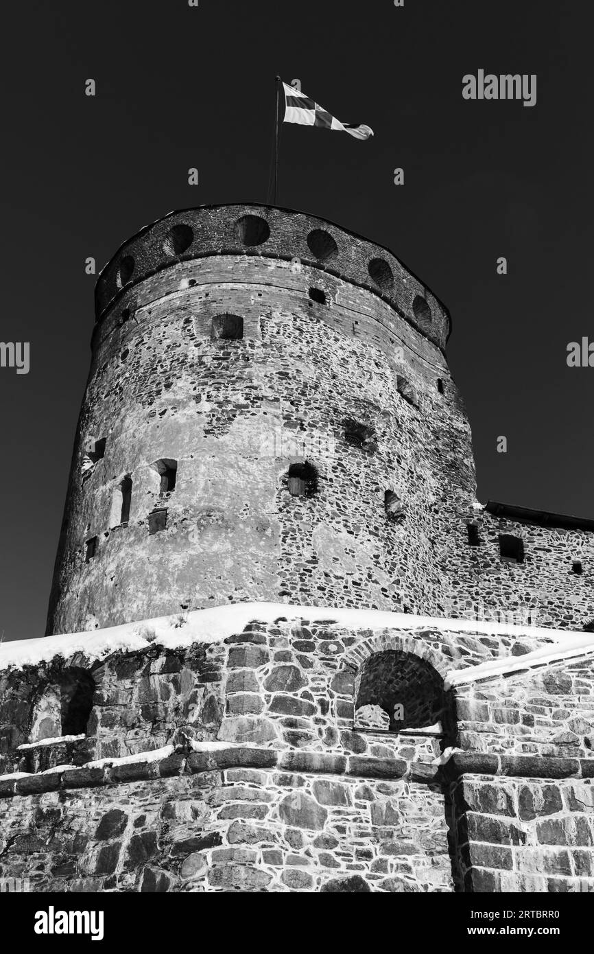 Olavinlinna fortress is under dark sky, vertical black and white photo. This is a 15th-century three-tower castle located in Savonlinna, Finland. The Stock Photo