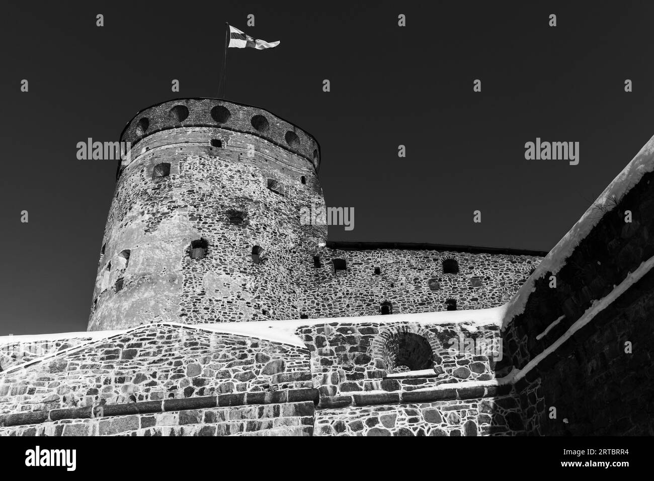 Round tower of Olavinlinna is under dark sky, black and white photo. It is a 15th-century three-tower castle located in Savonlinna, Finland. The fortr Stock Photo