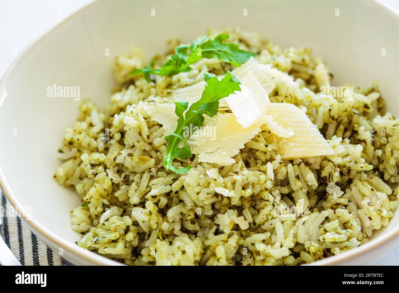 Green pesto risotto with parmisan, white marble background, closeup