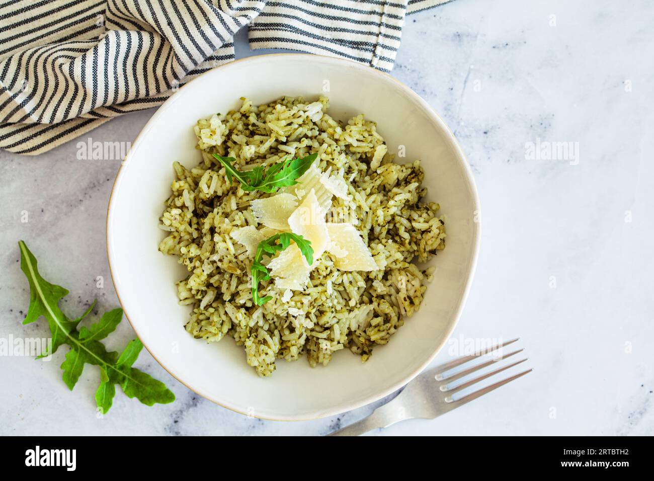 Green pesto risotto with parmisan, white marble background, top view. Stock Photo