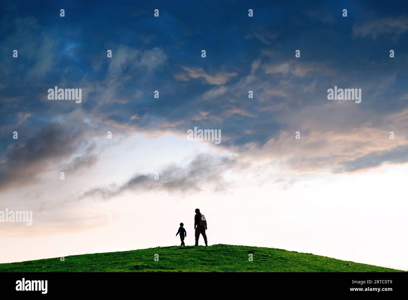 Silhouette of a person following child against minimalist landscape Stock Photo