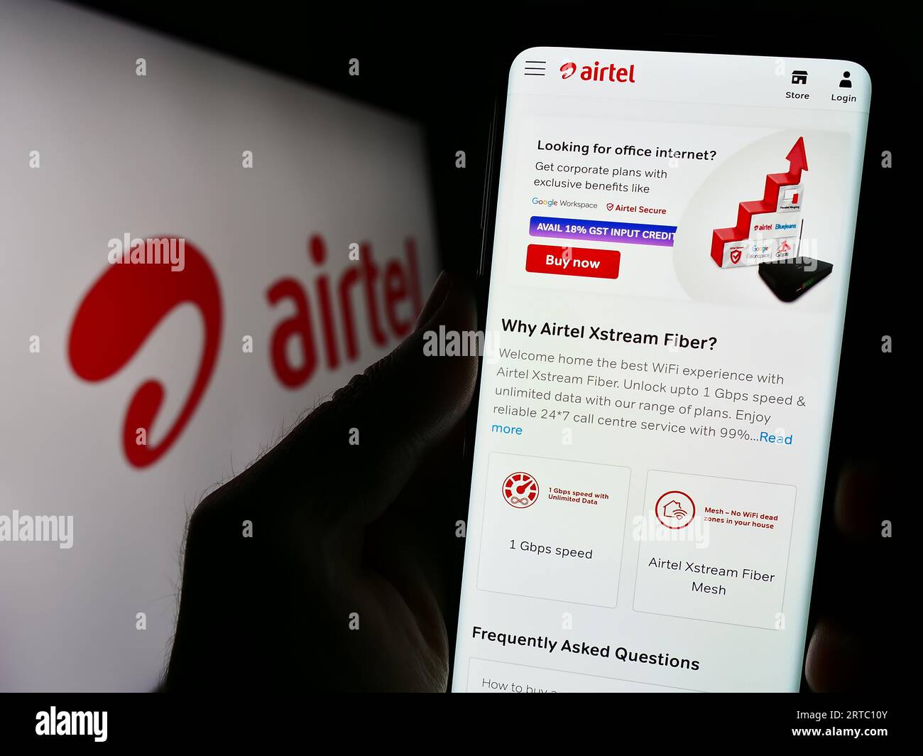 Person holding cellphone with website of telecommunications company Bharti Airtel Limited on screen with logo. Focus on center of phone display. Stock Photo