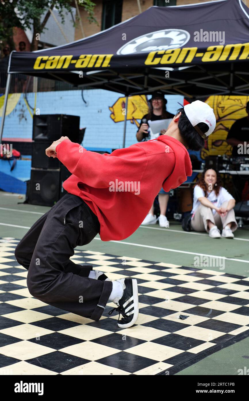 Break dancer in Red Hoodie back pants and black adidas sneakers - knee bends breakdancing performance, competition and battles Woolloomooloo, Sydney Stock Photo