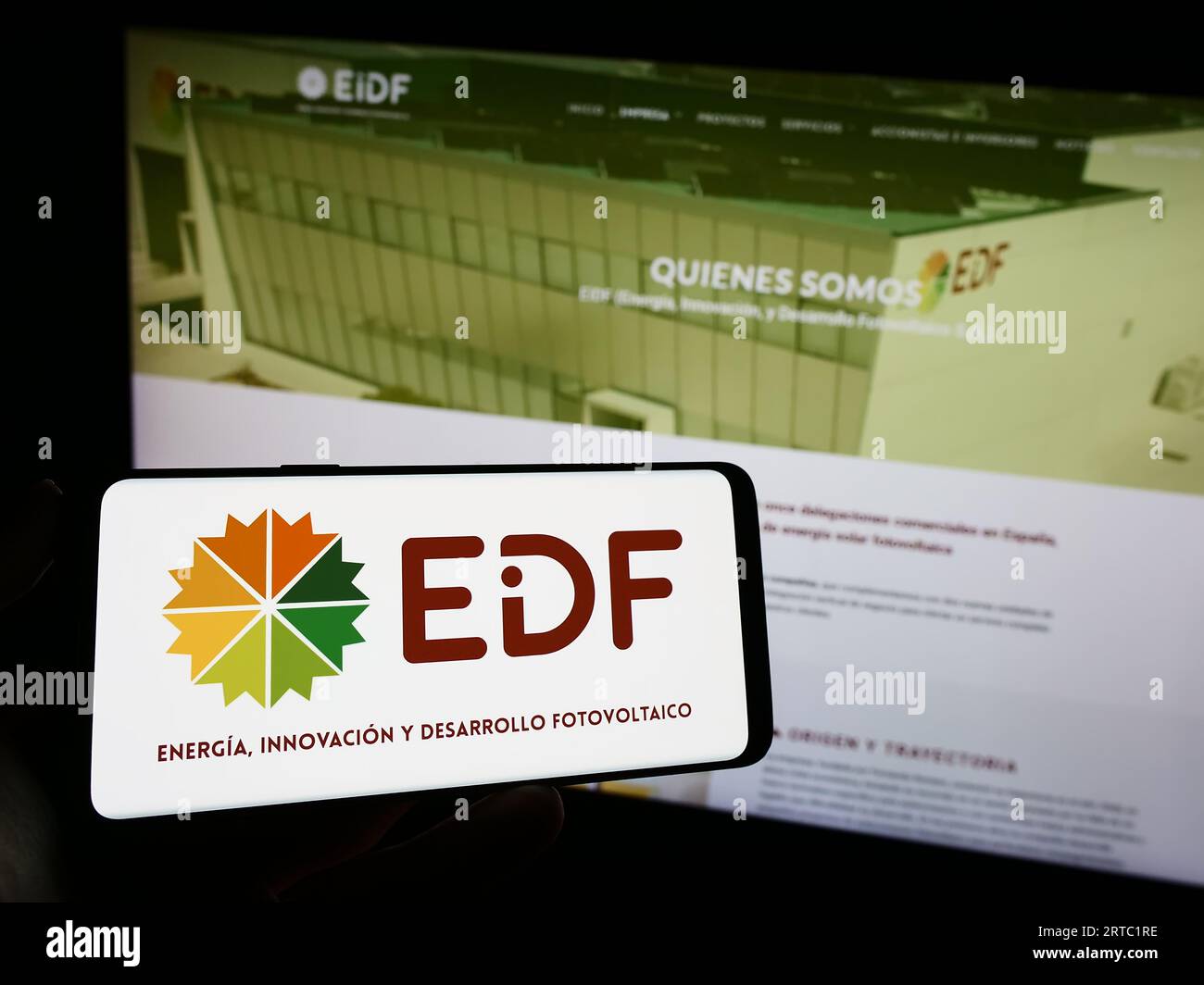 Person holding mobile phone with logo of Spanish photovoltaics company EiDF Solar on screen in front of business web page. Focus on phone display. Stock Photo