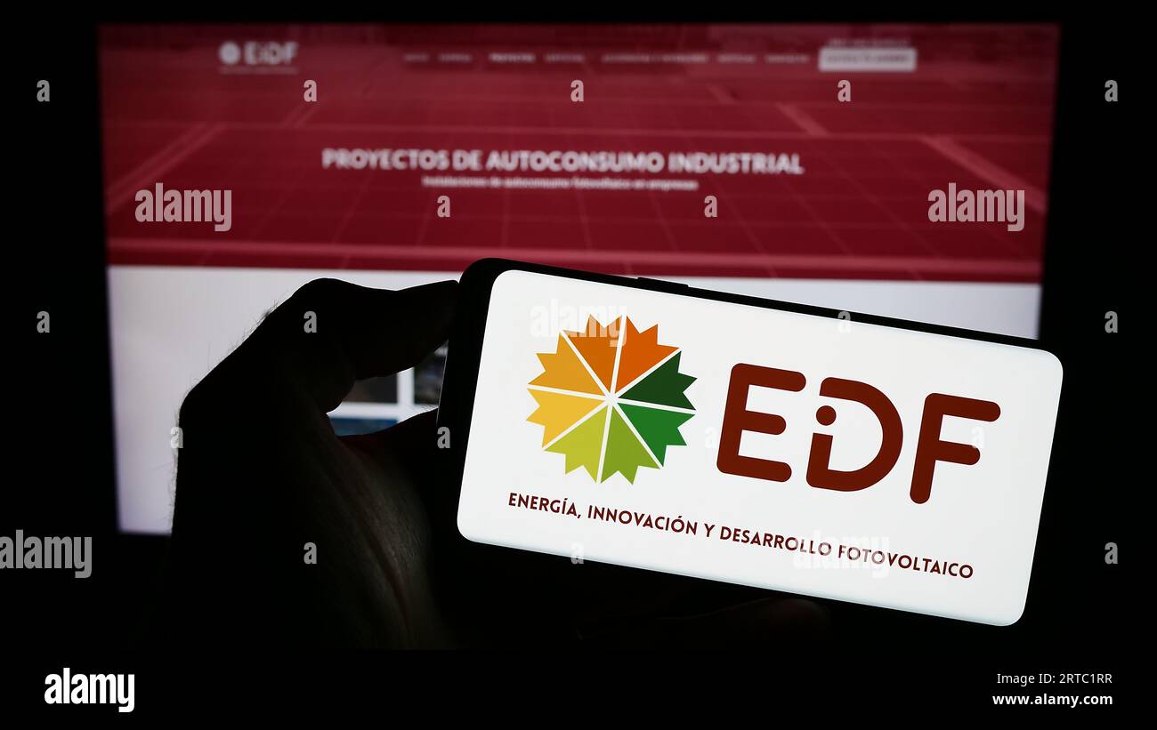 Person holding cellphone with logo of Spanish photovoltaics company EiDF Solar on screen in front of business webpage. Focus on phone display. Stock Photo