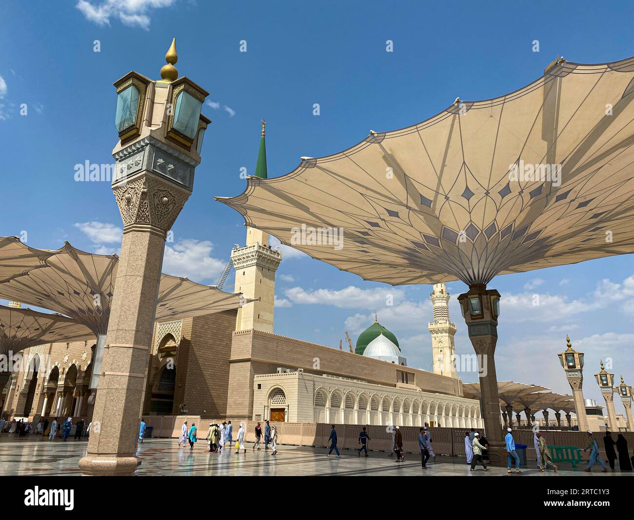 Medina, Saudi Arabia - August 22, 2023: Pilgrims walk underneath giant umbrellas at Nabawi Mosque compound. Canopies at Masjid Nabawi in Medina, Saudi Stock Photo