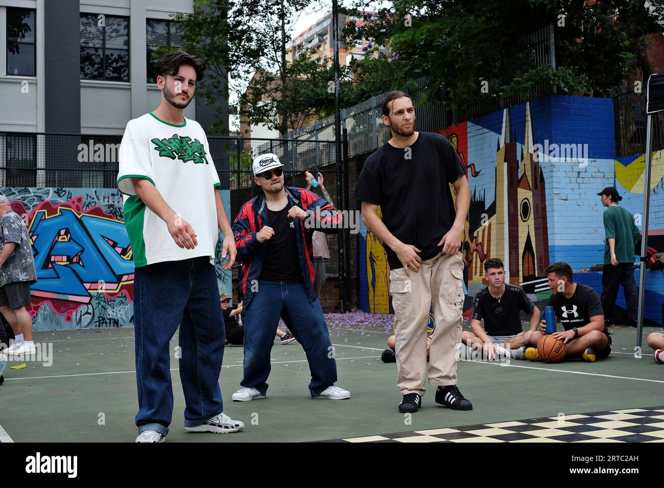 Three male dancers perform a breakdancing battle stand-off competitions and battles on the basketball courts of  Woolloomooloo, Sydney Stock Photo