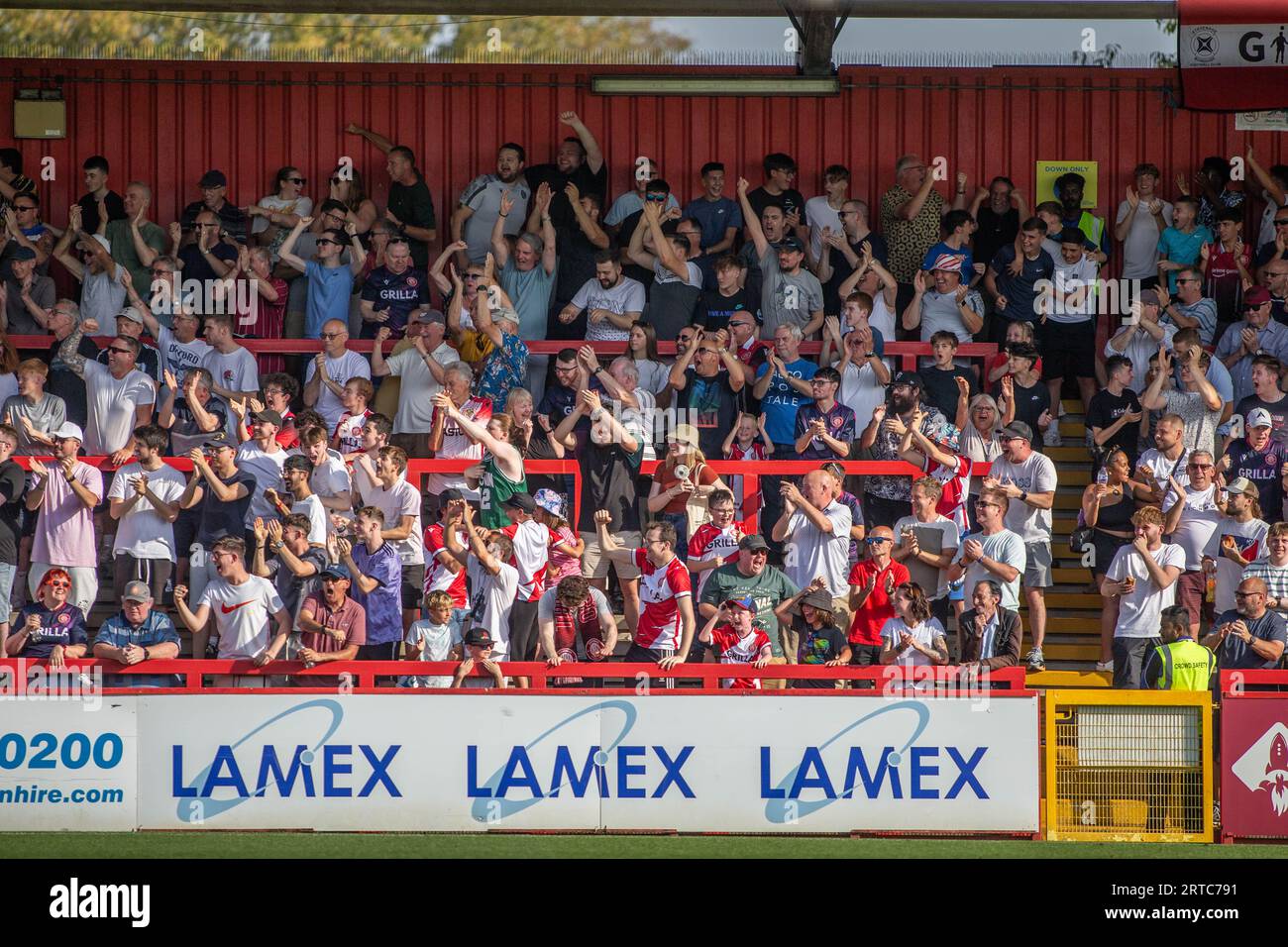 Football fans chanting, singing and celebrating in standing terrace at lower league ground