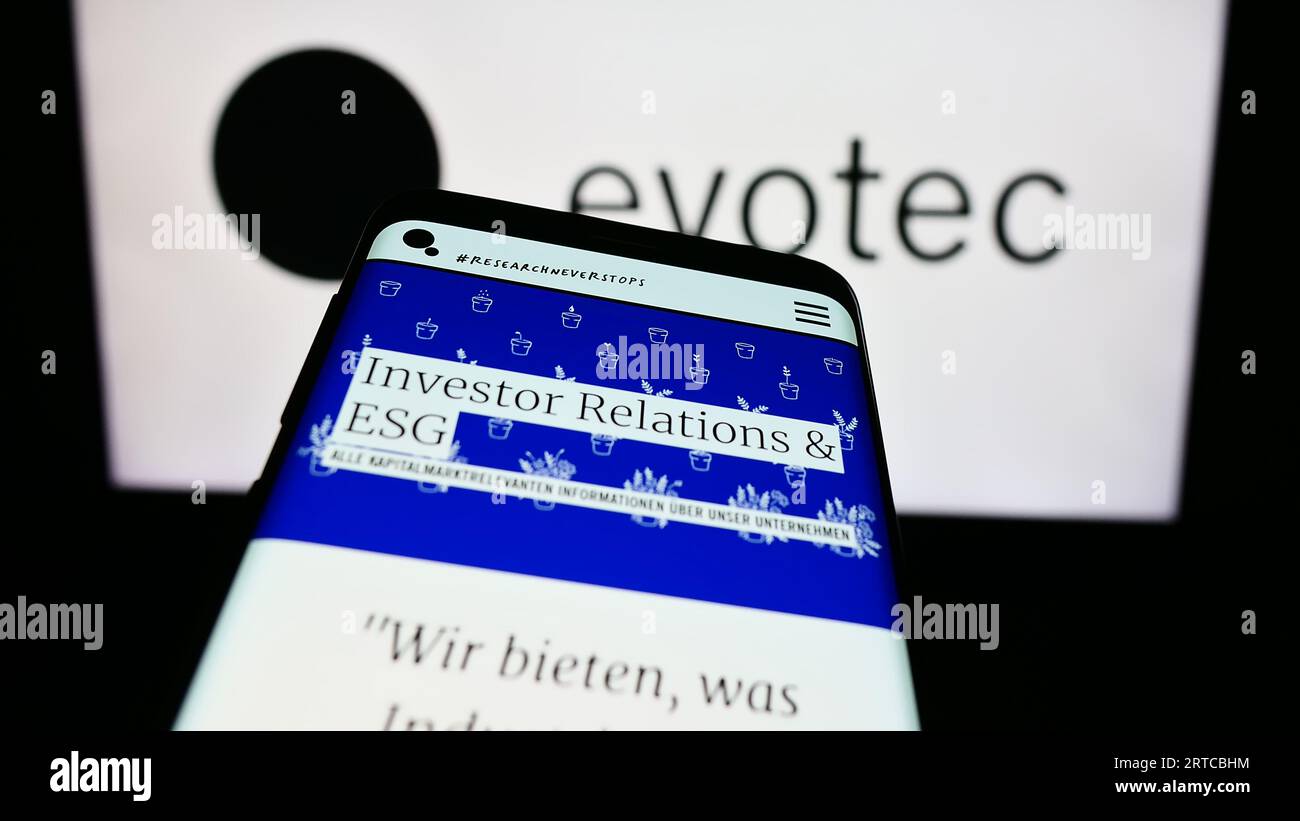 Smartphone with webpage of German drug discovery company Evotec SE on screen in front of business logo. Focus on top-left of phone display. Stock Photo