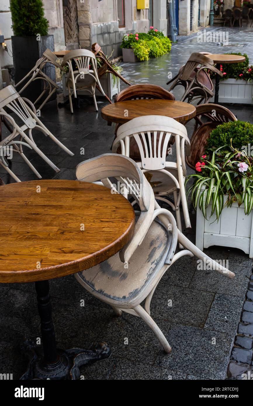 Empty wet wooden table and chairs on terrace of outdoor cafeteria