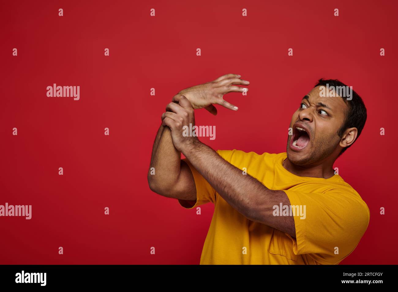 face expression, scared indian man in yellow tshirt losing control of