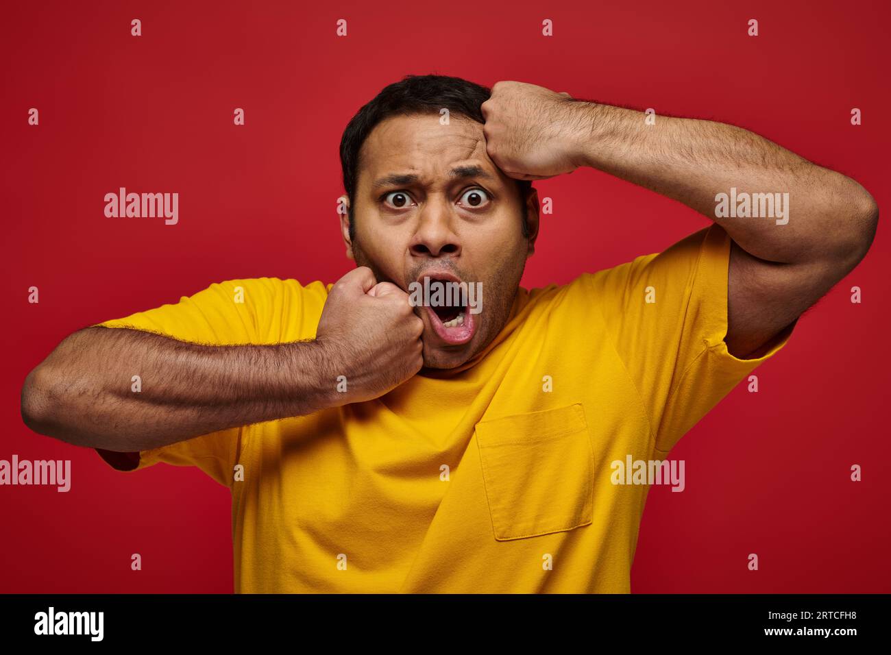 face expression, shocked indian man in yellow tshirt punching himself