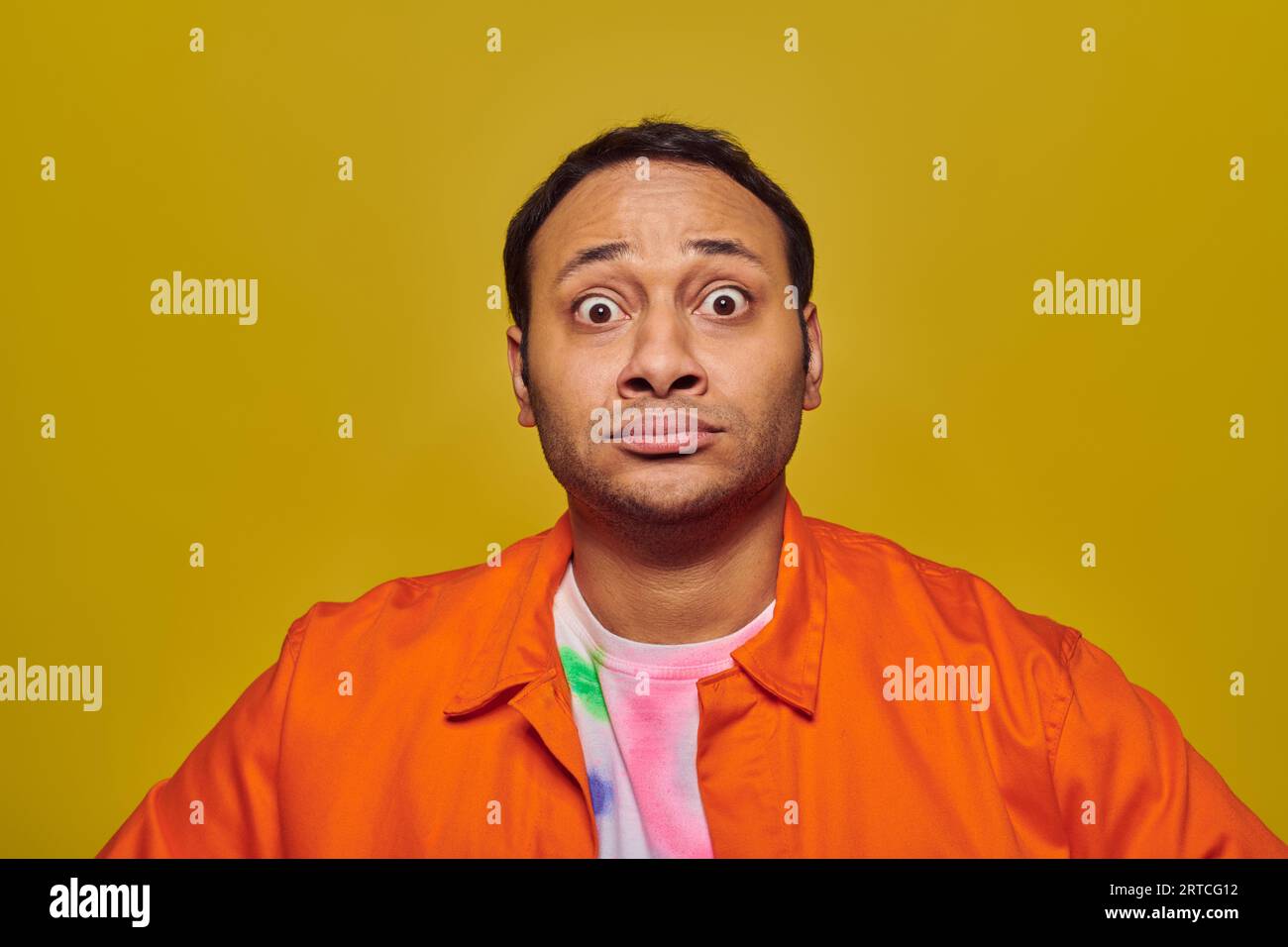 shocked indian man with eyes wide open looking at camera isolated on yellow, face expression Stock Photo
