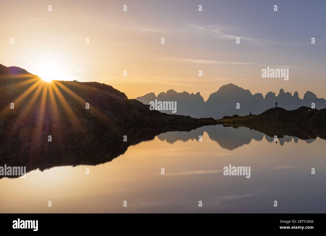 Sunrise with sunstar at the black lake of Cornisello with view of the Brenta Dolomites, Carisolo, Pinzolo, Trentino, Italy Stock Photo