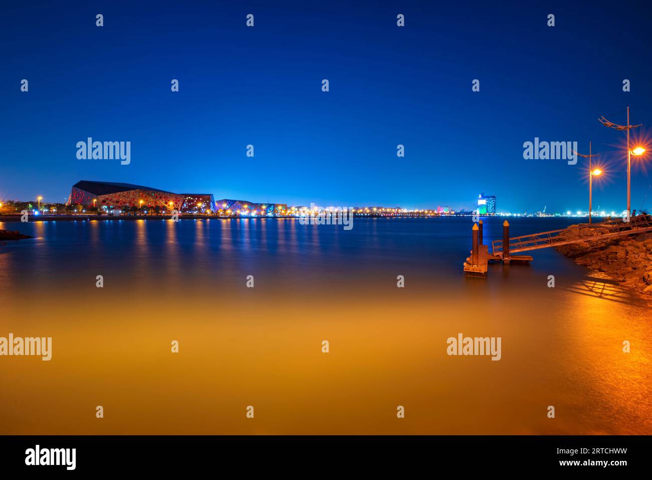 City skyline view from the beach bridge. Buildings and shore visible. Night view of Kuwait city and lights Stock Photo