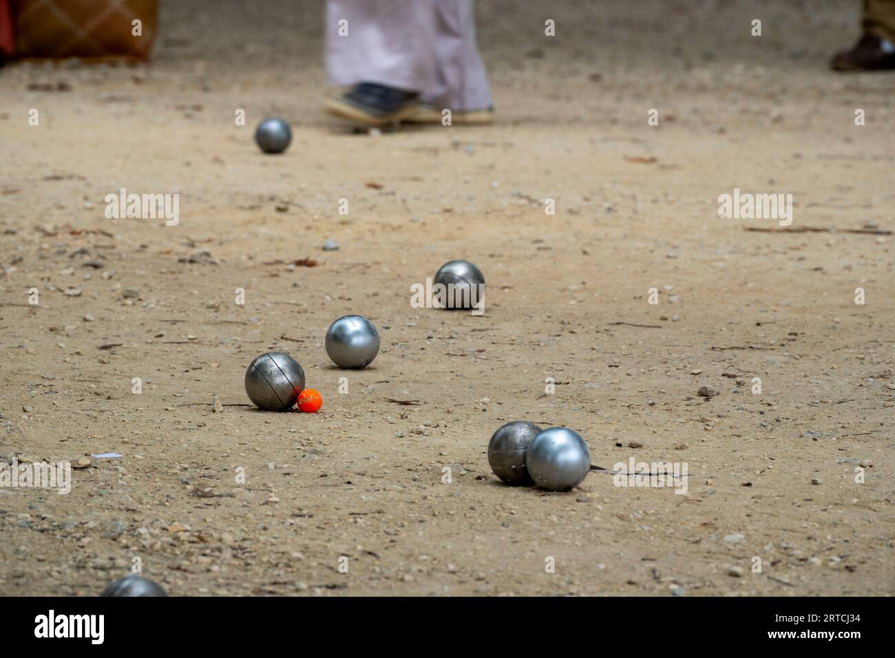 Petanque ball boules bowls on a dust floor, photo in impact. Game of petanque on the ground