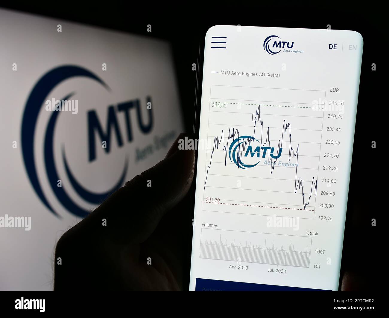 Person holding cellphone with webpage of German aviation company MTU Aero Engines AG on screen in front of logo. Focus on center of phone display. Stock Photo