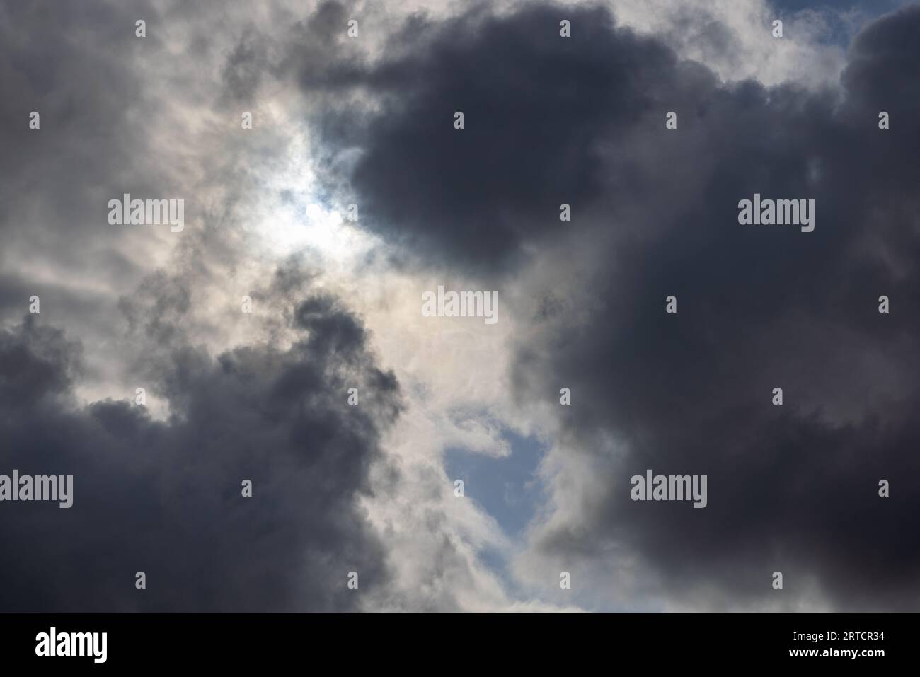 zenith pointed incoming storm cloudscape with heavy clouds and sun between them, full-frame real life photo Stock Photo