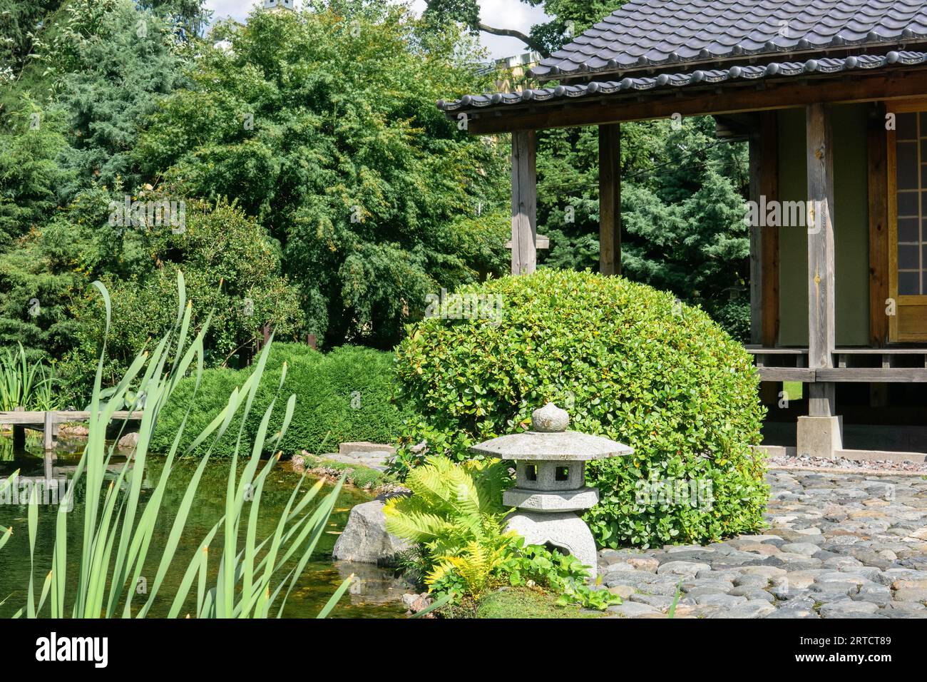 stone lantern on the shore of a pond in a Japanese garden with a tea house Stock Photo