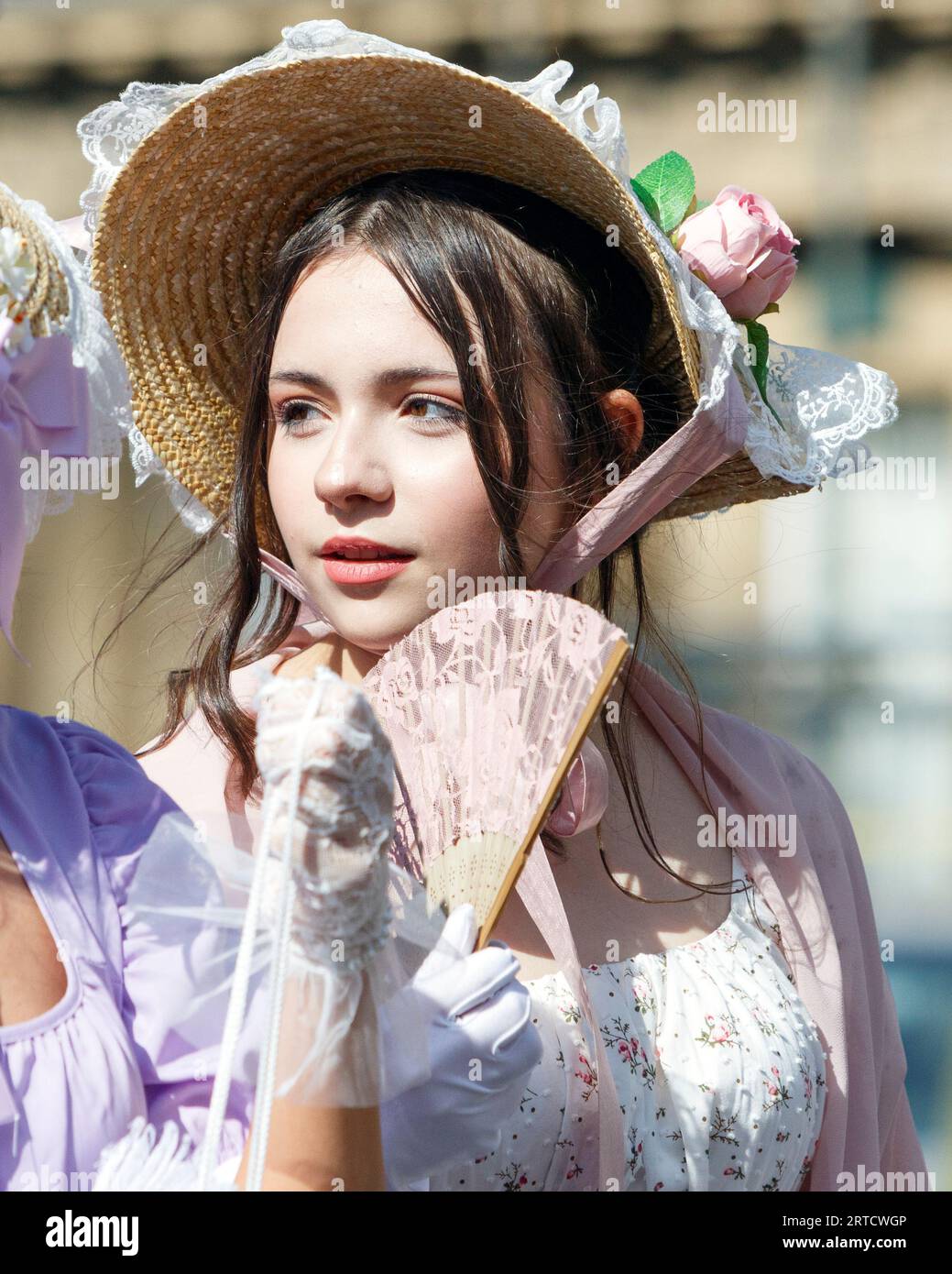 A Jane Austen festival fan taking part in the world-famous Grand Regency Costumed Promenade is pictured as she walks around the Circus in Bath, UK Stock Photo