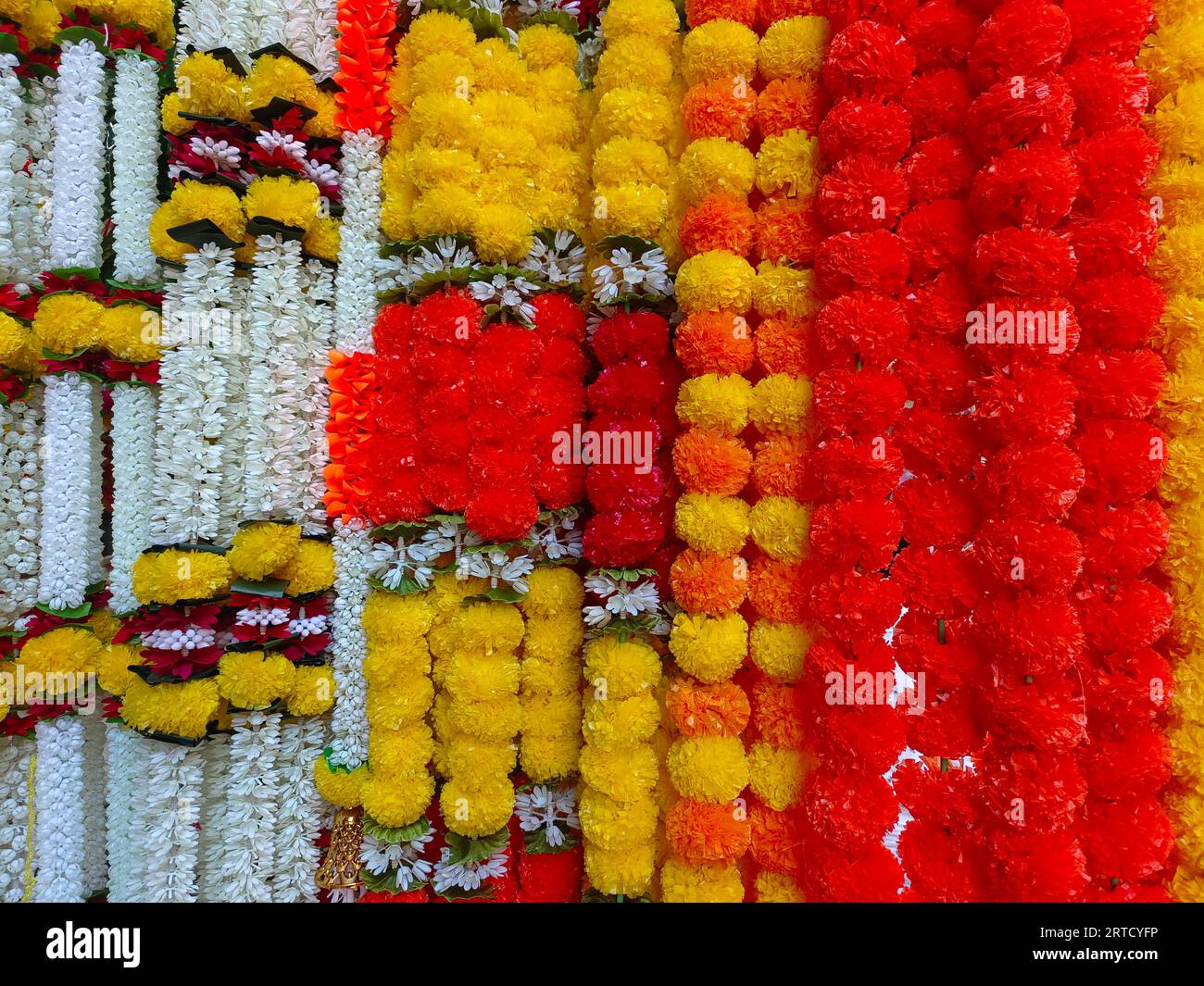 Multicolour artificial flowers used for Diwali festival decoration,  hanging inside a shop, on the day before Diwali and Ganesh festival Stock Photo