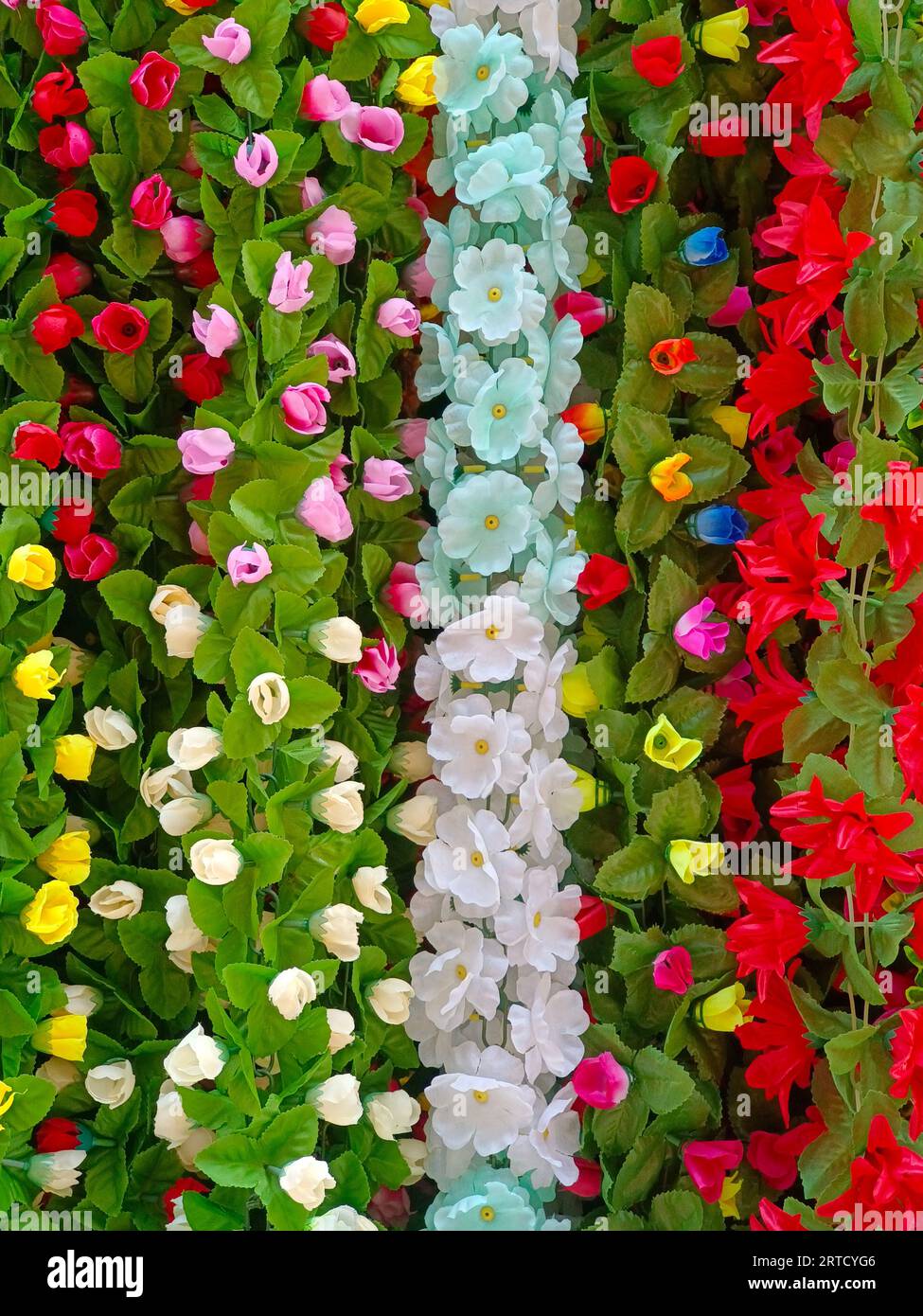 Multicolour artificial flowers used for Diwali festival decoration,  hanging inside a shop, on the day before Diwali and Ganesh festival Stock Photo