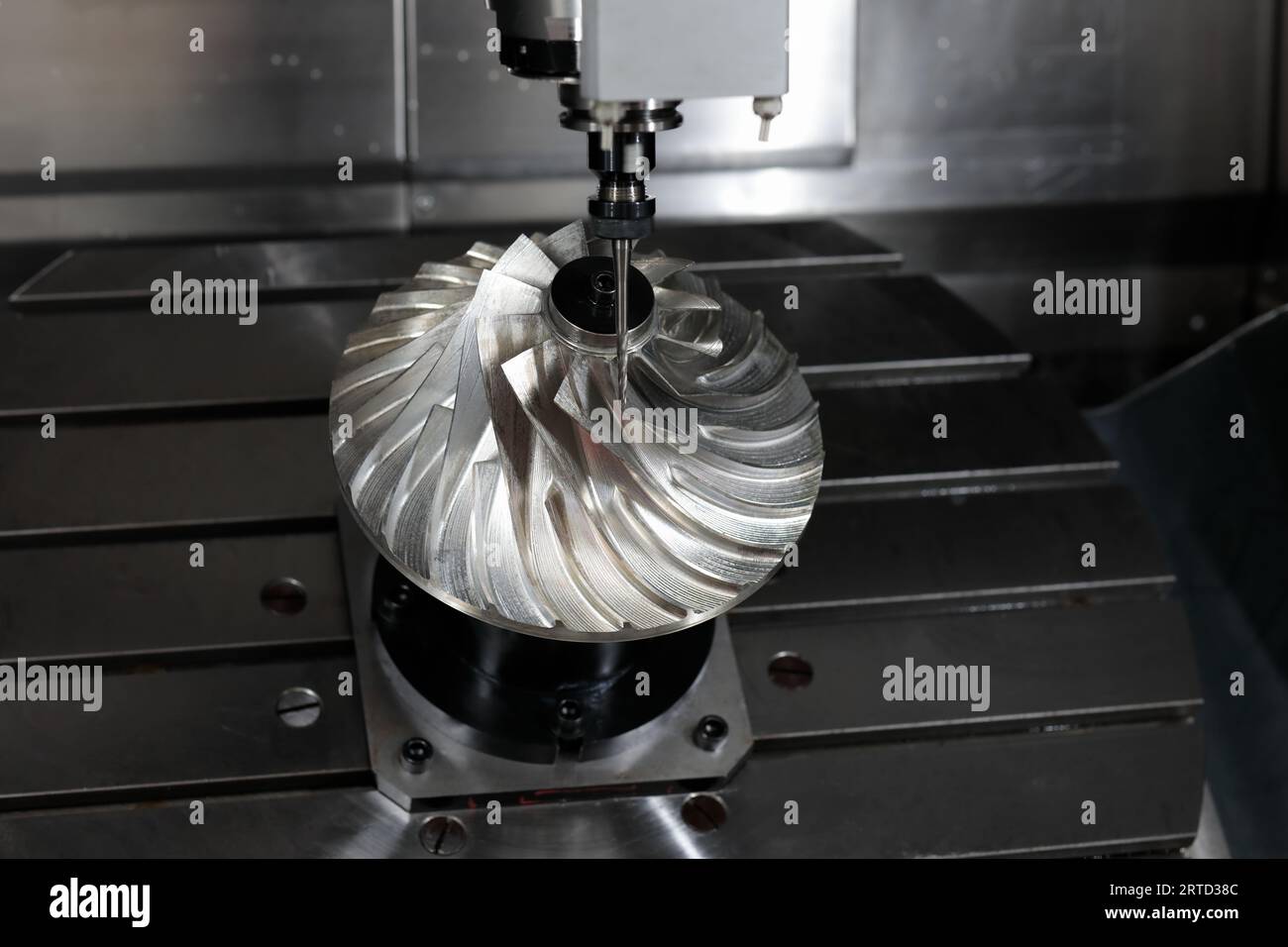 Turbine wheel manufacturing by 5 axis CNC milling machine. Selective focus. Stock Photo