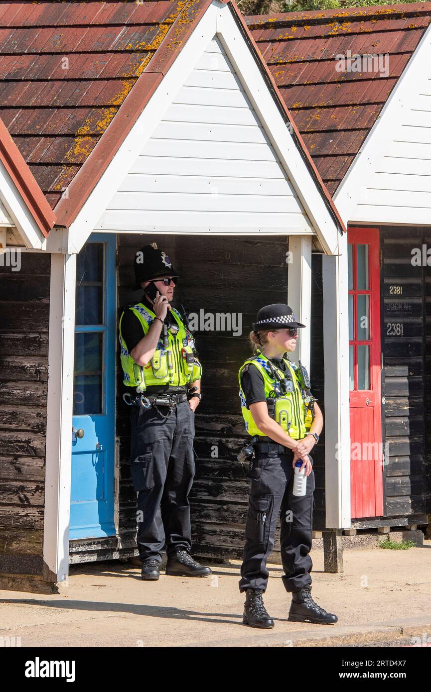 two police officer shading from the sun using a beach hut. two police constables on patrol shading from the hot sun using a seaside beach hut. Stock Photo