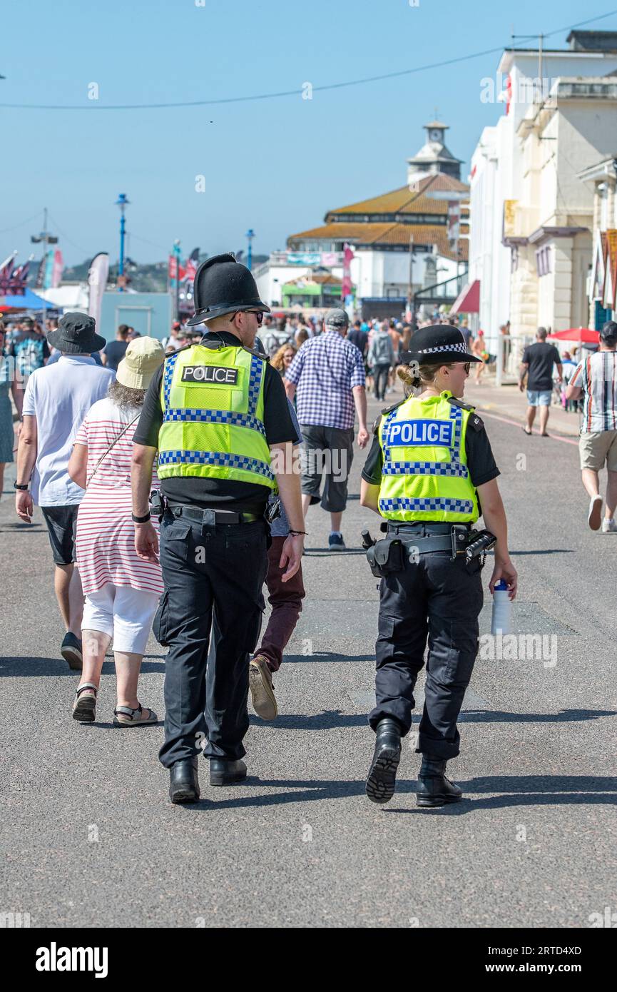 police officer on the beat patrolling the seafront at bournemouth during a busy summer holiday season. commuity policing officers walking together Stock Photo