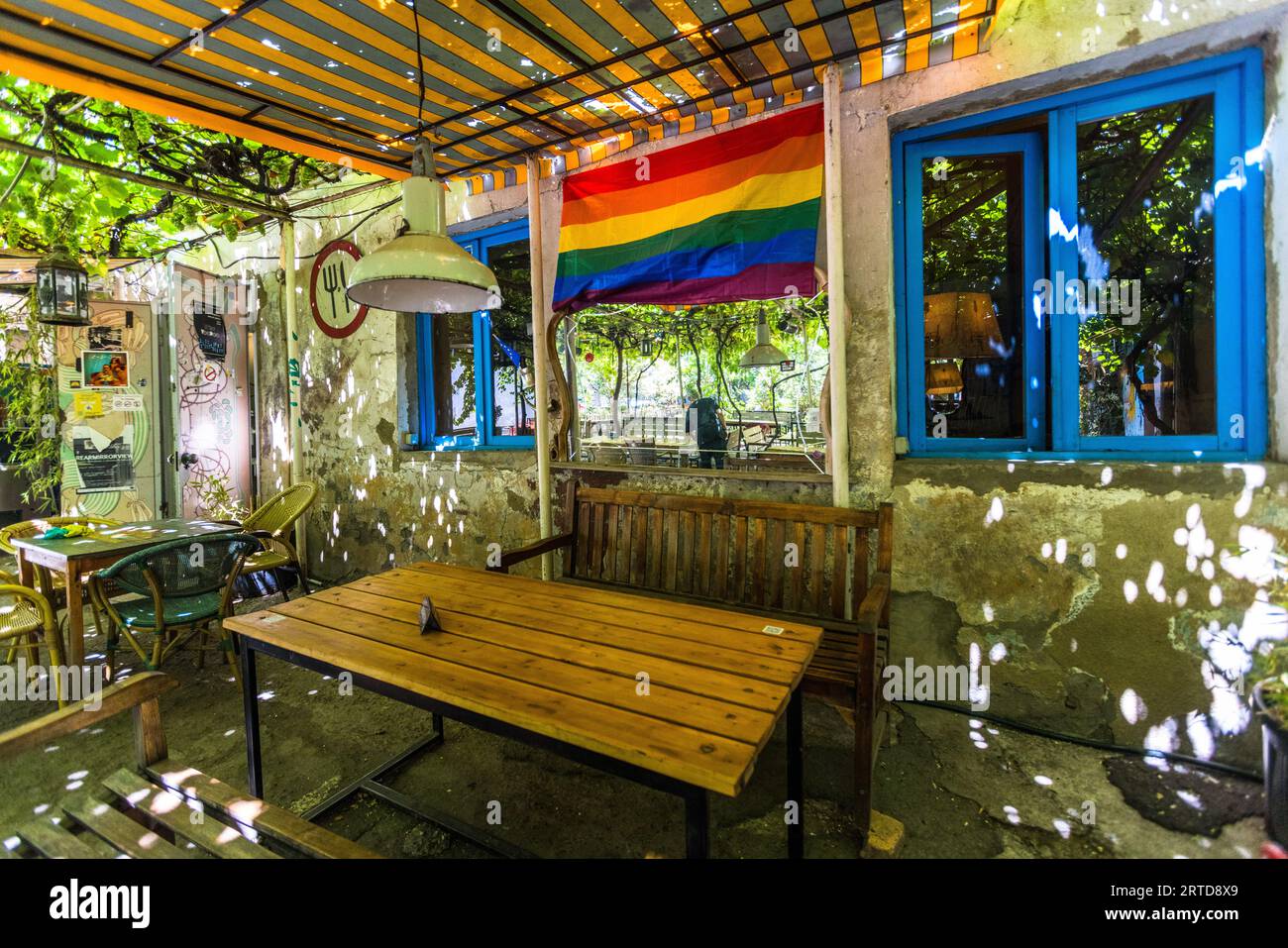 The outdoor area of Sofia Melnikova’s Fantastic Douqan restaurant on Tabukashvili Street, Tbilisi, Georgia. The tables are set beneath a dense canopy of vines through which sunlight filters; a rainbow flag on the wall identifies the venue as an LGBTQ-friendly meeting place in Tbilisi. Revaz Tabukashvili Street, Garetubani, Mtatsminda, Sololaki, Mtatsminda District, Tbilisi, 0108, Georgia Stock Photo
