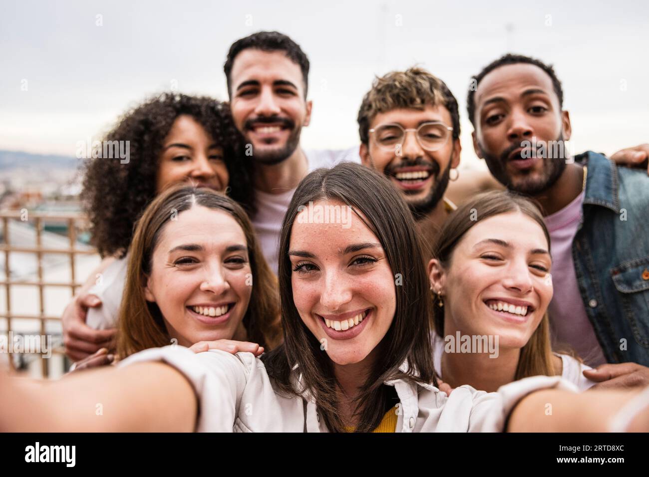Diverse cheerful group of friends taking a selfie in a rooftop party ...