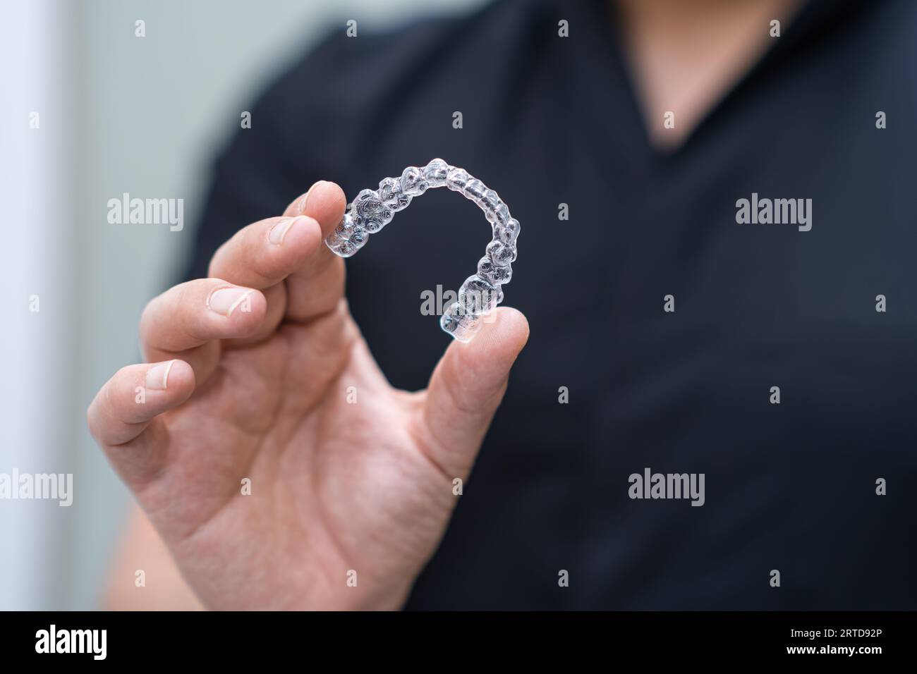 Dentist in black uniform holding clear aligners of orthodontic