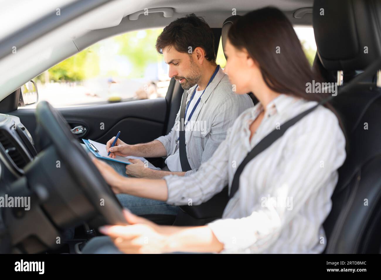 Handsome young man instructor examining woman driver Stock Photo