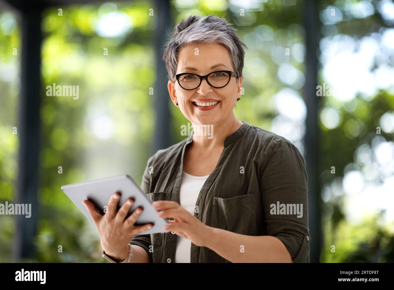 Happy middle aged woman freelancer using digital tablet Stock Photo