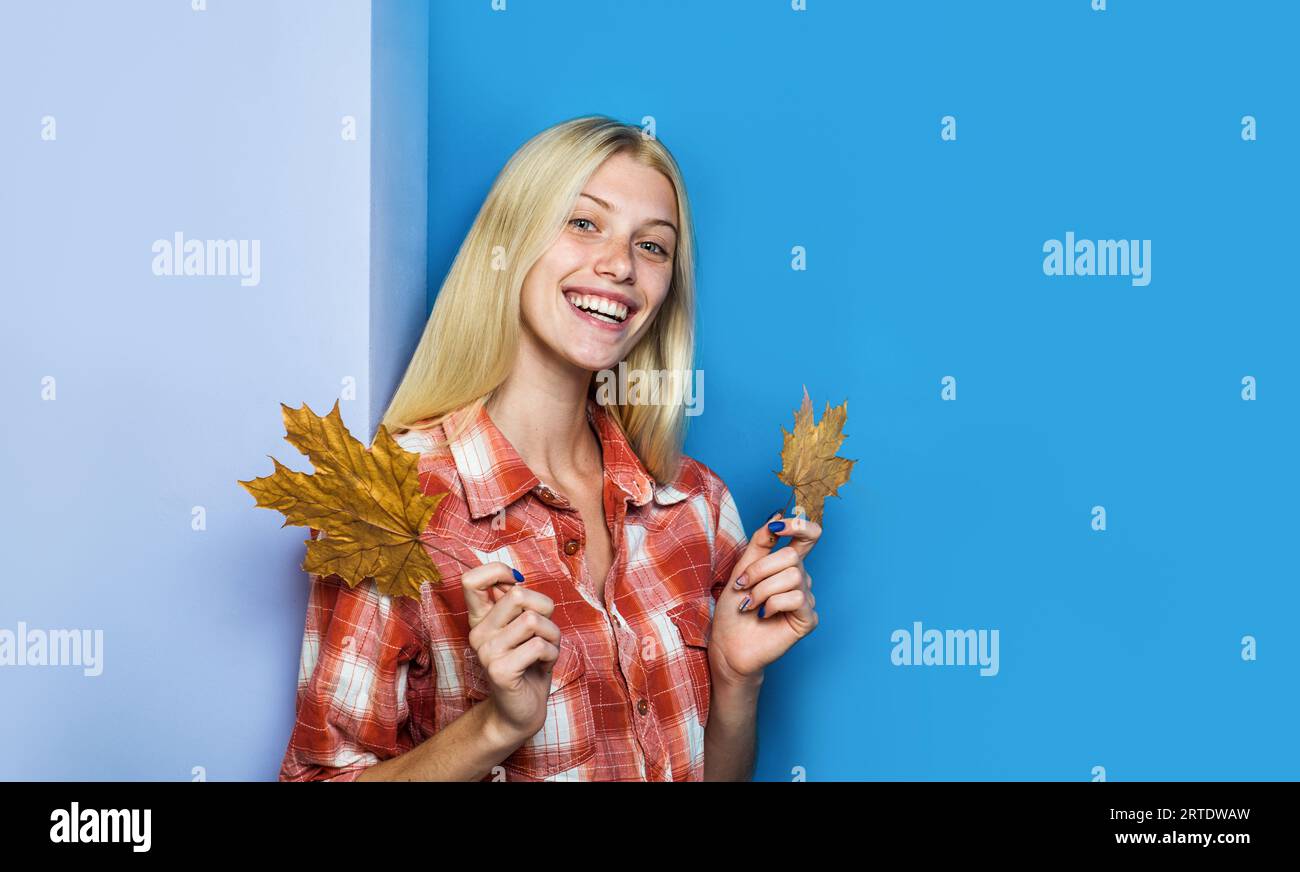 Smiling blonde girl in plaid shirt with autumn leaves. Happy autumn woman in casual wear with maple leaf. Fashion female model with fall foliage Stock Photo