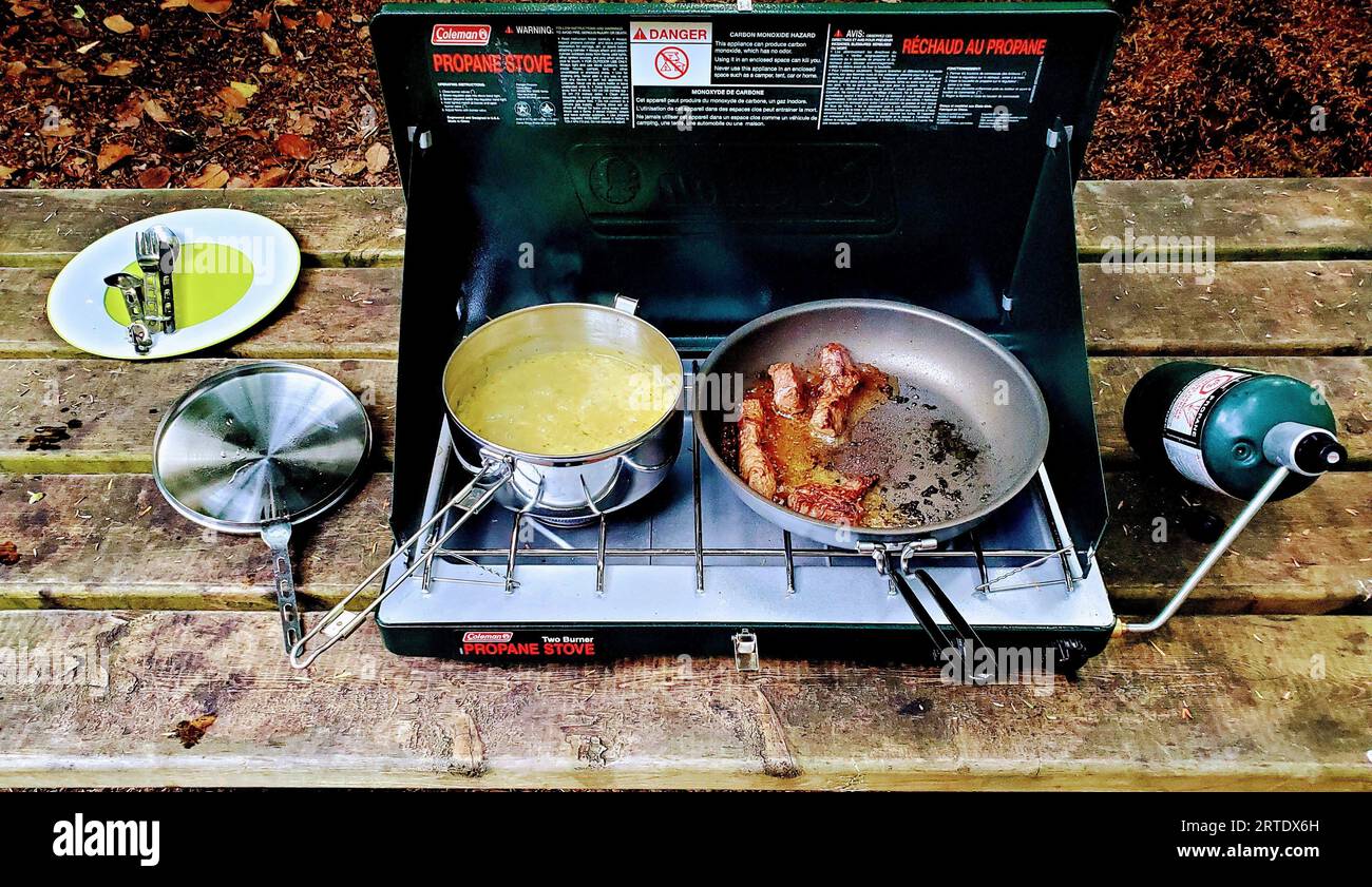 An outdoor scene of a Coleman camping stove cooking a meal of Uncle Ben