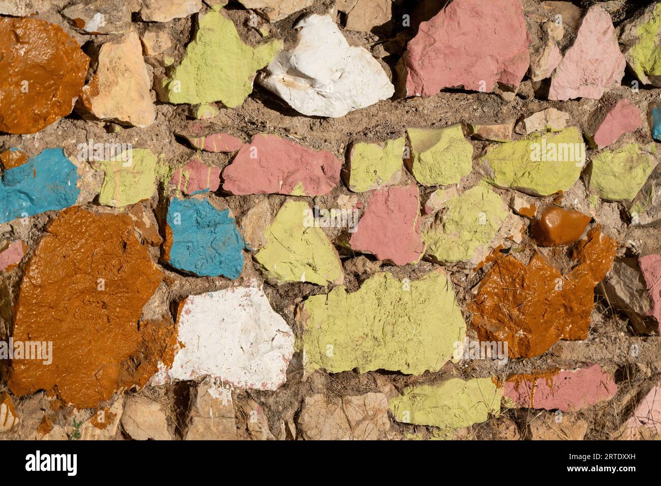 Old stone wall painted in various colors. Stock Photo