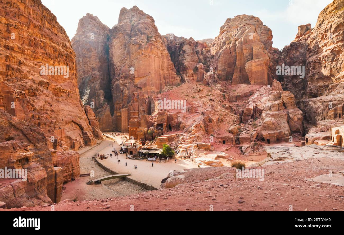 Tourist walk by caves of tombs in ancient city of Petra, Jordan. It is know as the Loculi. Petra has led to its designation as UNESCO World Heritage S Stock Photo