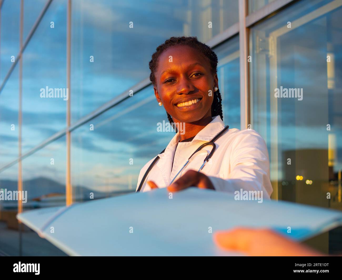 Young female doctor taking a folder in front of a hospital Looking at camera Stock Photo