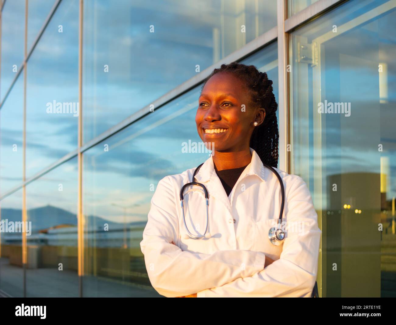 young female doctor crossing her arms in front of a hospital Stock Photo