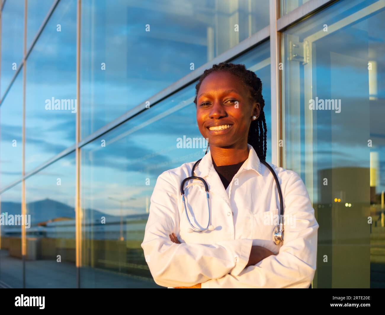 young female doctor crossing her arms in front of a hospital Stock Photo