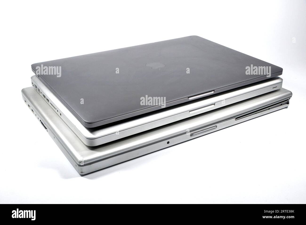 a stack or collection of 3 generations of Apple MacBook Pro laptop models isolated against a white studio background showing thinner bodies Stock Photo