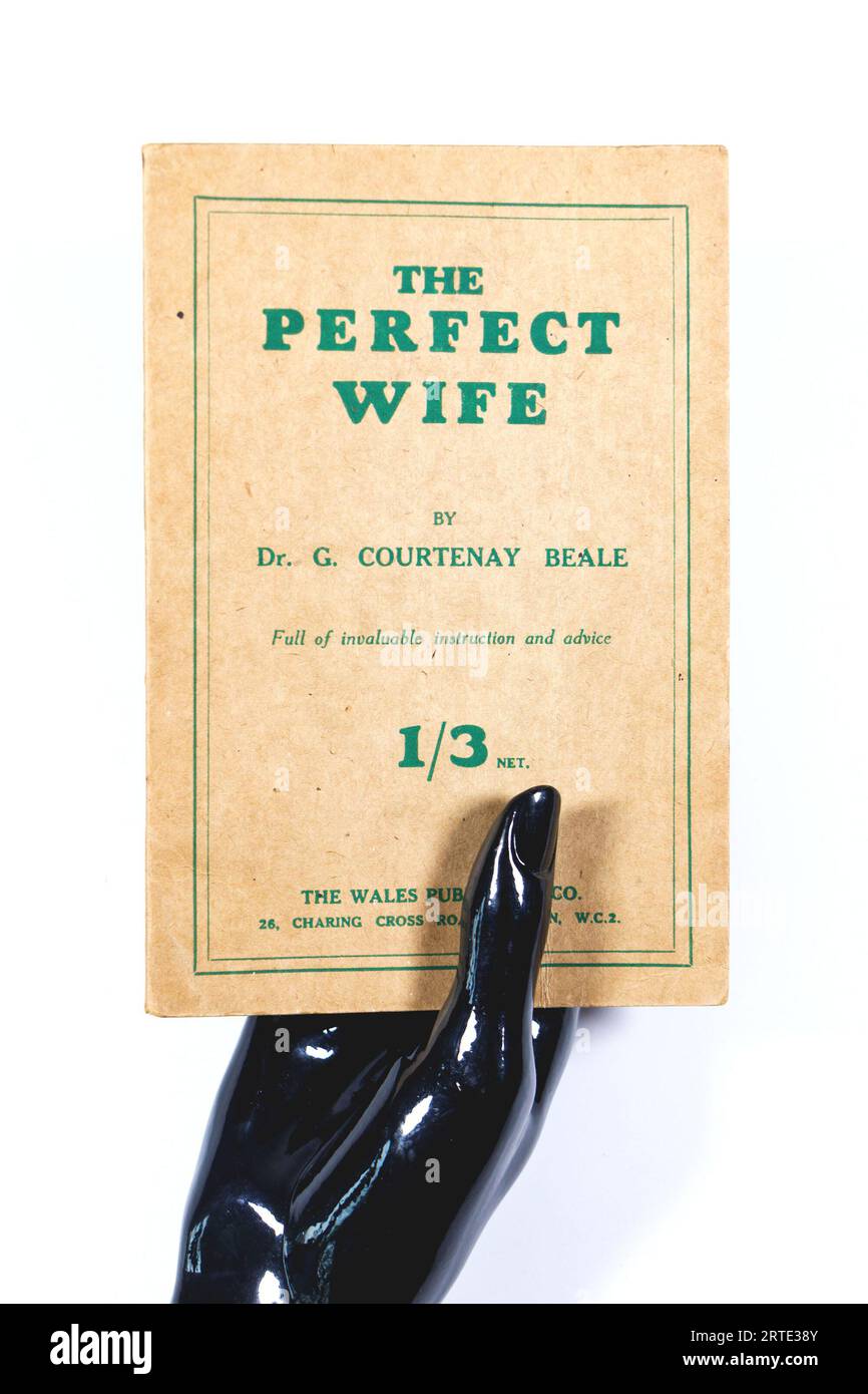 vintage book the perfect wife by Dr G Courtenay Beale isolated against a white studio background wales publishing company - shiny black mannekin hands Stock Photo