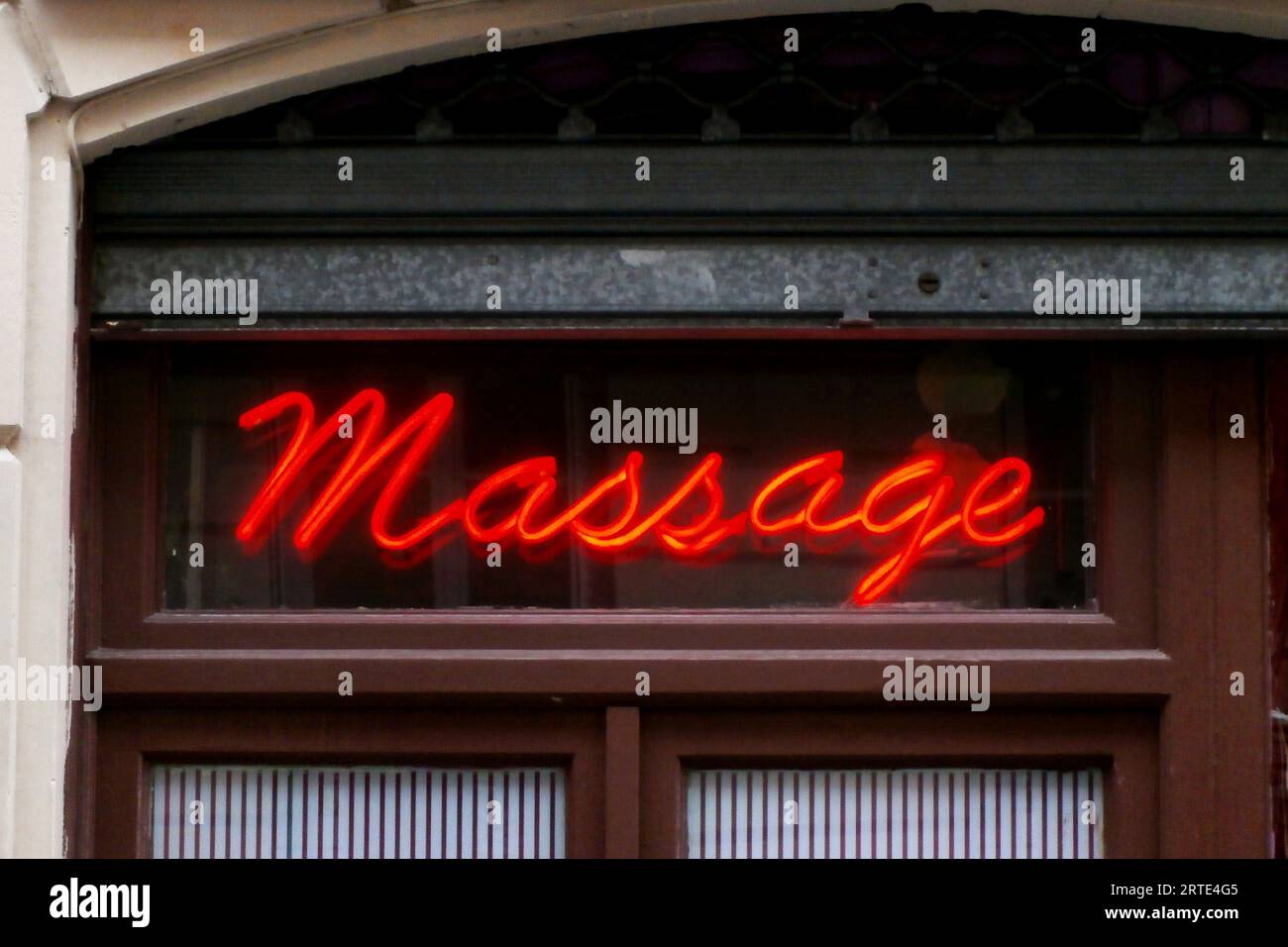 Closeup on a red neon light shaped in the word "massage" in the window of a Chinese massage