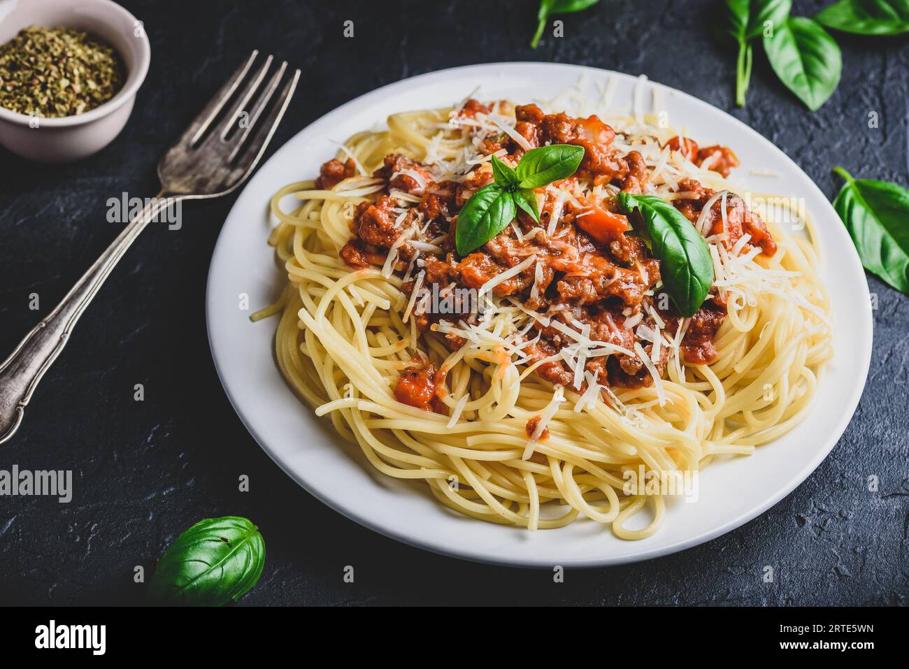 Spaghetti with bolognese sauce, grated parmesan cheese and fresh basil leaves Stock Photo