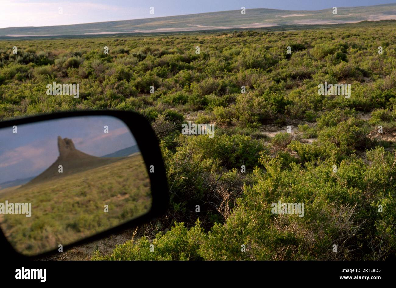 Boars Tusk outcropping in the rear view mirror of a car in the Jack Morrow Hills, Red Desert of Wyoming, USA; Wyoming, United States of America Stock Photo