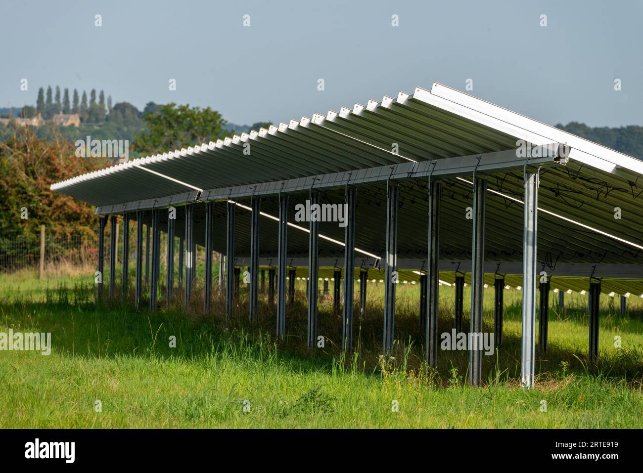 Side,detailed view of solar panels,working units,glowing with and reflecting late afternoon sunlight,showing distant countryside houses on the horizon Stock Photo