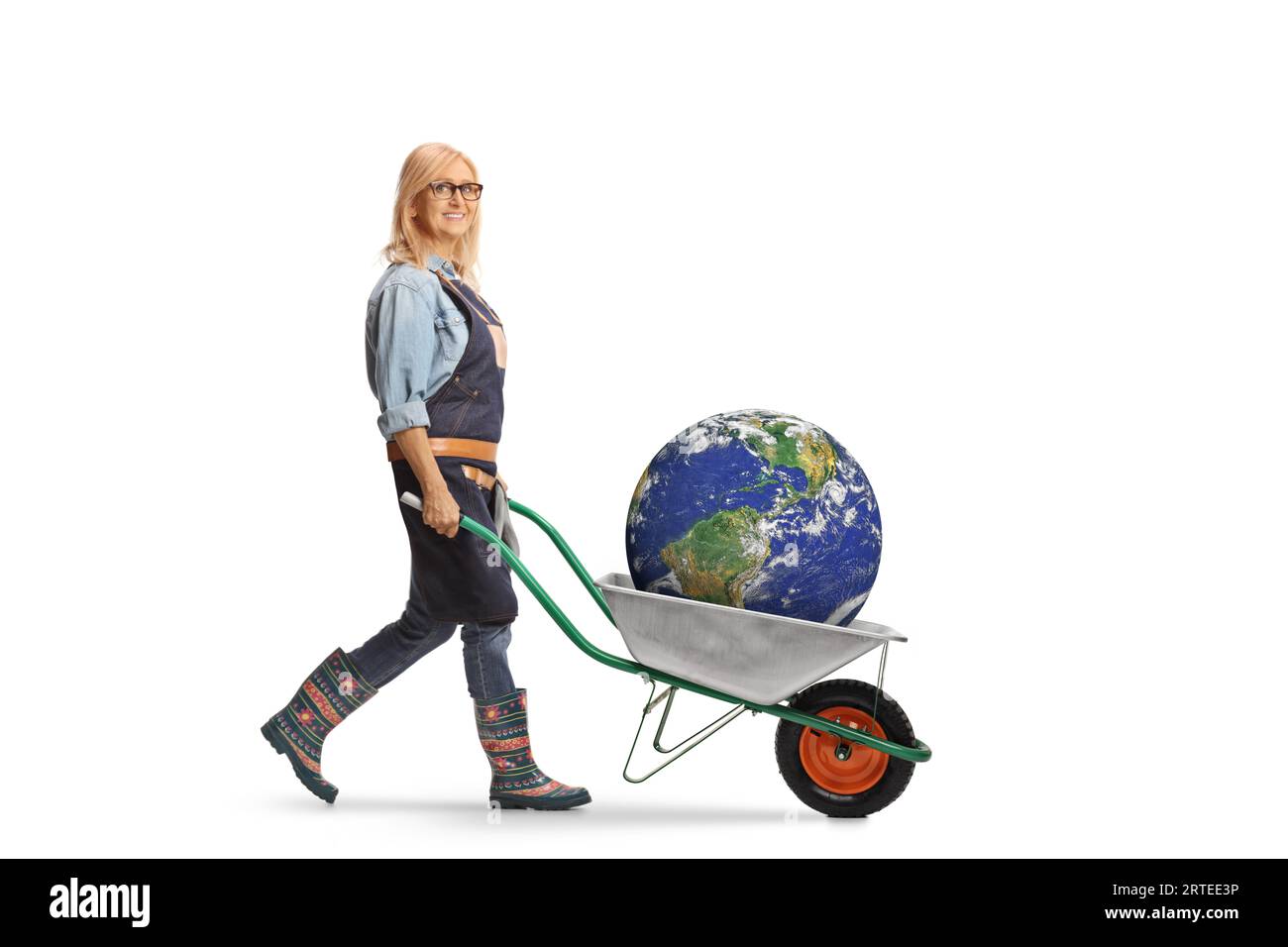Full length profile shot of a female gardener pushing a wheelbarrow with the plant earth inside isolated on white background Stock Photo