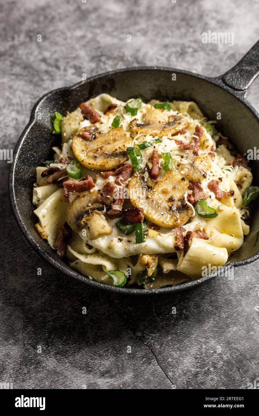 Tagliatelle with mushrooms, diced bacon, and herbs Stock Photo