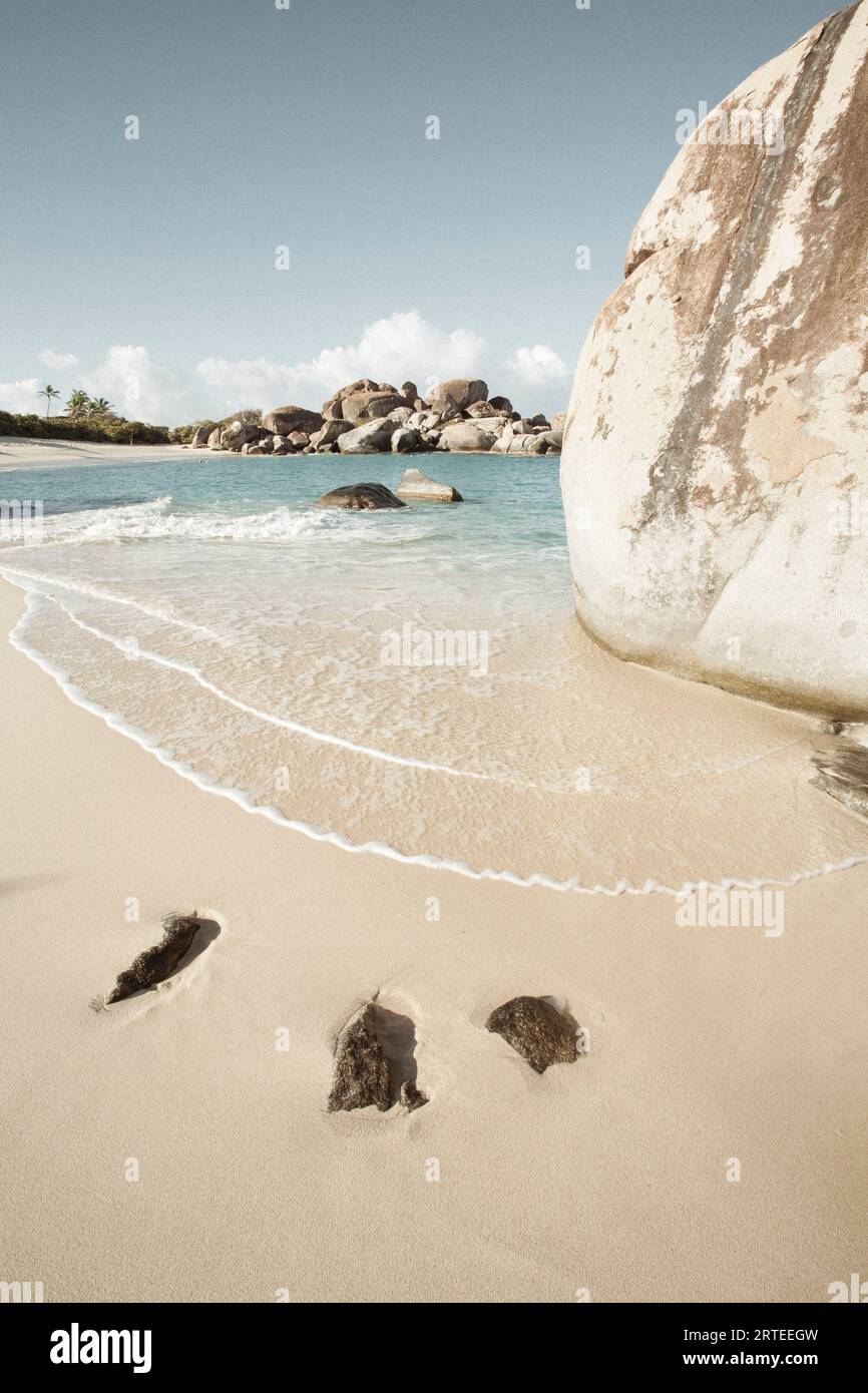 Close-up view of the sea surf forming zigzag patterns on the sand with large, boulders on the shores of The Baths, a famous beach in the BVI's Stock Photo